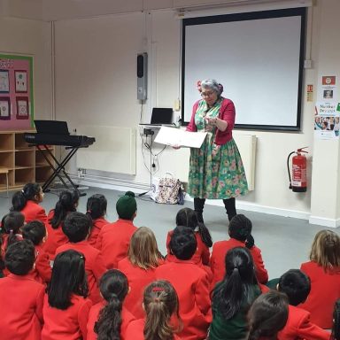 Vie Portland giving a talk at a school, holding her book up to show the children.